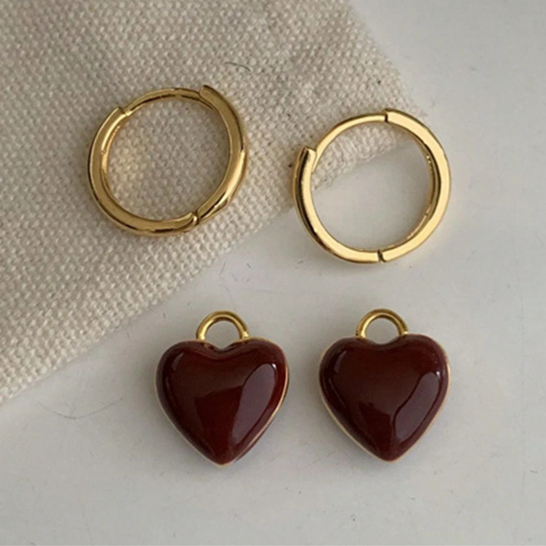 Pendientes de aro dorados con colgante de corazón rojo, estilo elegante y moderno de Vega Madrid en imagen.
