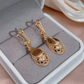 Pendientes colgantes Merle de Vega Madrid con diseño elegante y detalles metálicos en acabado brillante.