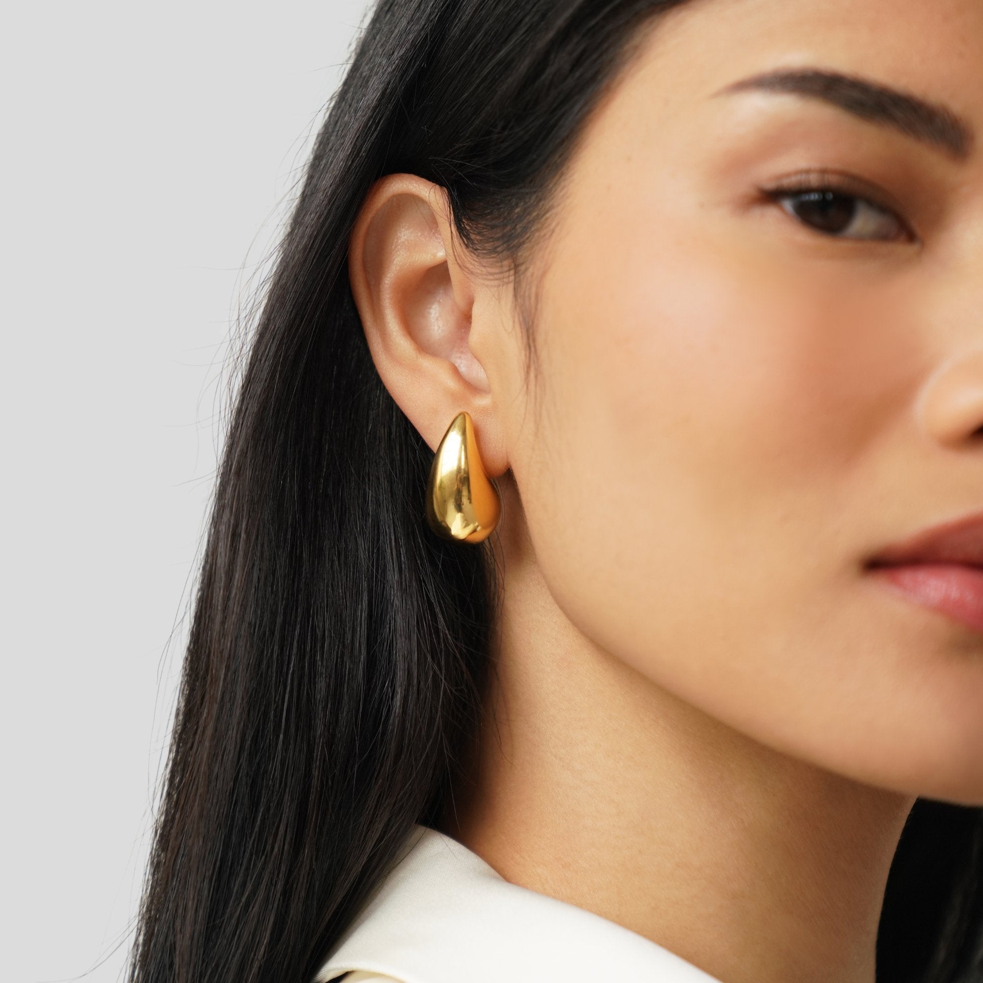 Pendientes colgantes Ame Gold de Vega Madrid, de gota de oro brillante y elegante, en un fondo neutro.