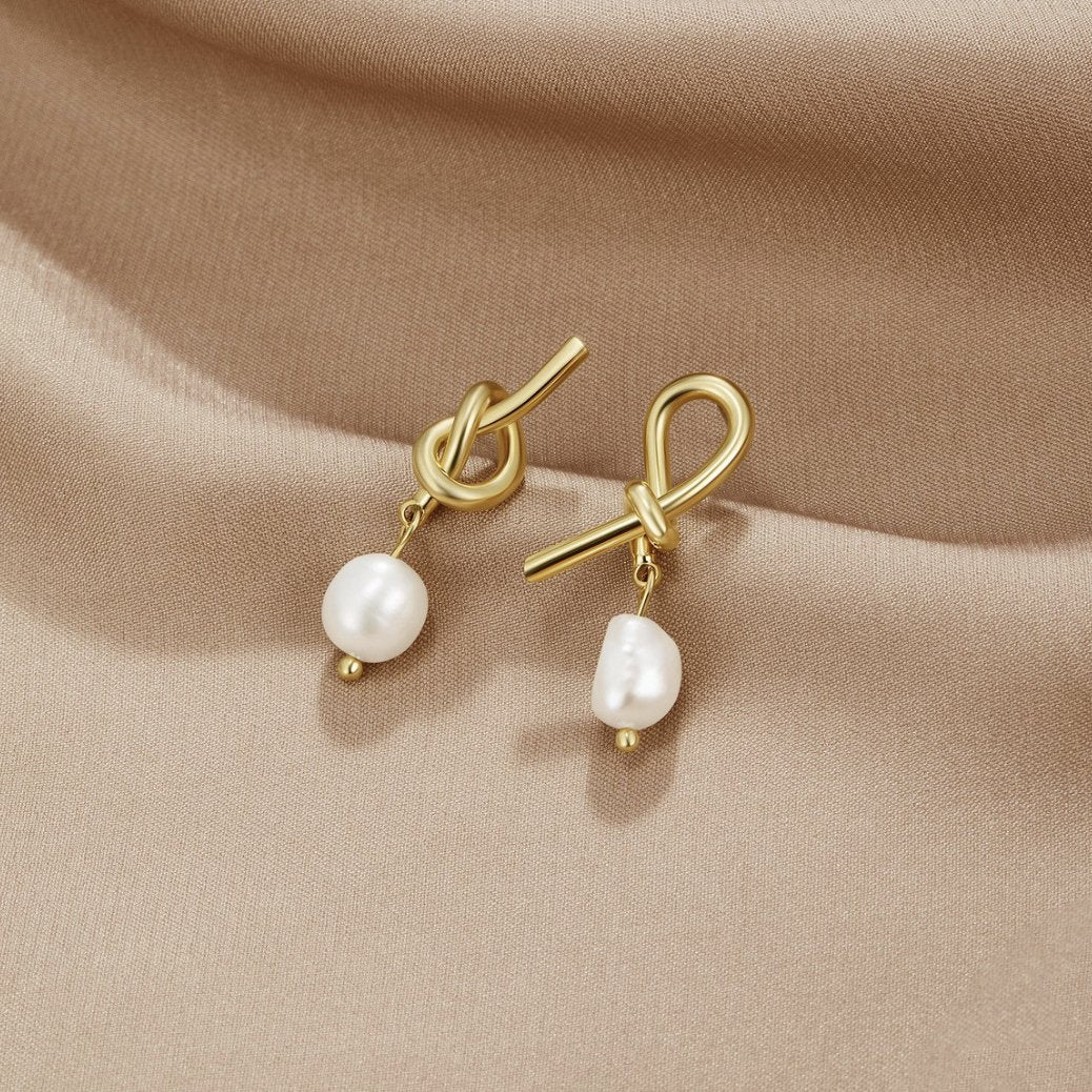 Pendientes dorados con nudo y perlas de agua dulce de Vega Madrid, detalles elegantes en forma de aro con perlas blancas naturales.
